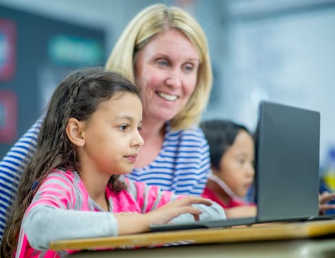 Teacher and young student looking at a laptop