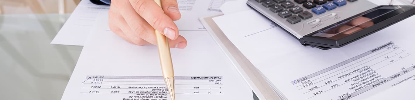 Mains tenant un stylo au-dessus d’une feuille de papier