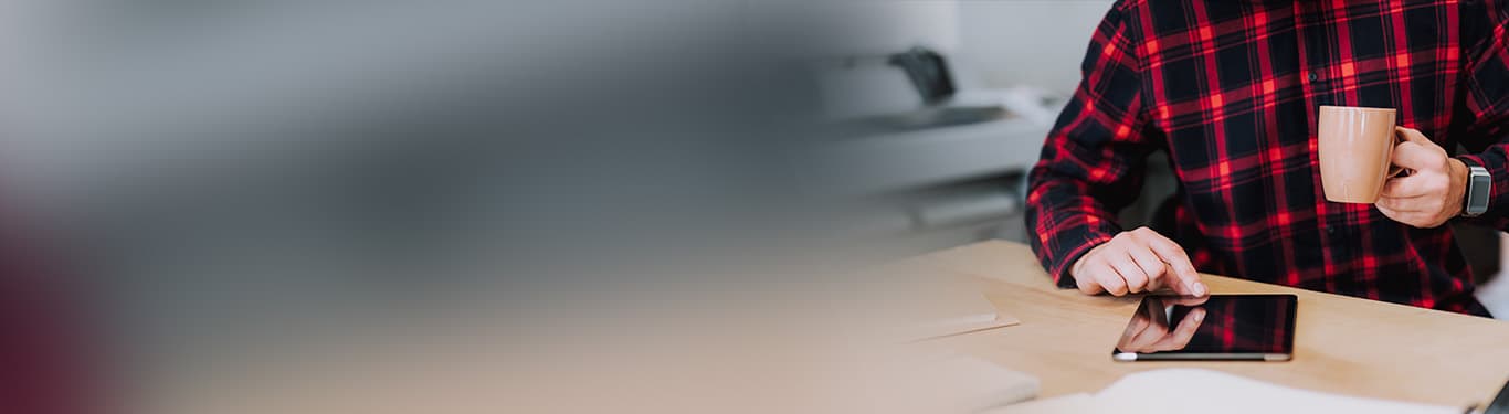 Mise au point sélective d'une tablette utilisée par un homme avec une imprimante grand format en arrière-plan